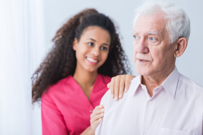 Female carer assisting and supporting senior man
