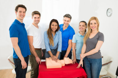 group of people standing near a cpr mannequin